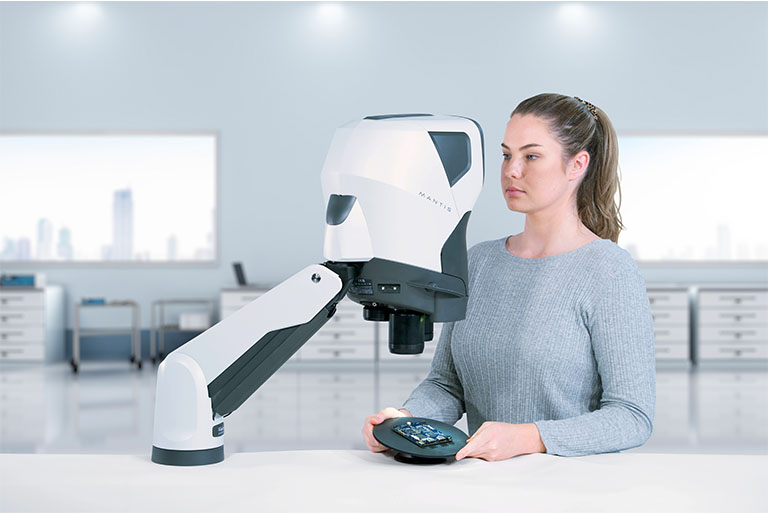 Woman Inspecting PCB using tilting base and Mantis PIXO 768x514px copy woman in workshop soldering a circuit board looking through Mantis stereo microscope
